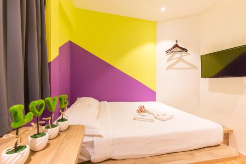 新加坡Fragrance Hotel - Balestier的色彩缤纷的客房设有一张床和盆栽植物