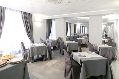 摩德纳普林西比酒店的餐厅设有灰色的桌椅和桌子。
