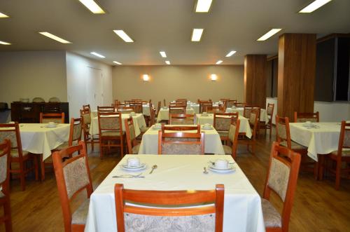 尼泰罗伊尼泰罗伊广场酒店的一间设有白色桌椅的用餐室