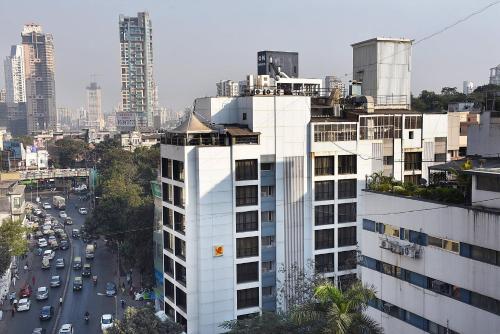 孟买The Shalimar Hotel, Kemps Corner的一条高大的白色建筑,旁边是一条有汽车的街道