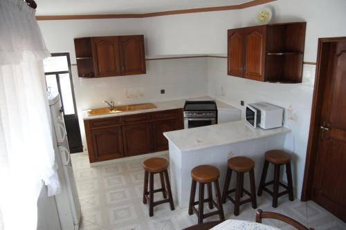 萨格里什阿塔里雅公寓式酒店的厨房配有木制橱柜和酒吧凳子。