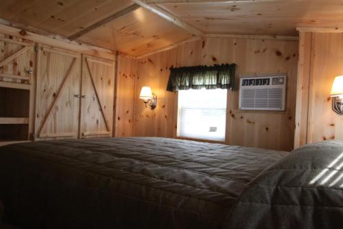 MiltonBlackhawk RV Campground Loft Cabin 11的卧室配有一张床铺,位于带木墙的房间内