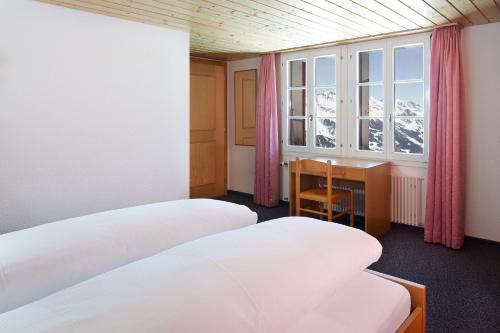格林德尔瓦尔德博格曼晨酒店的客房设有两张床、一张桌子和一个窗户。