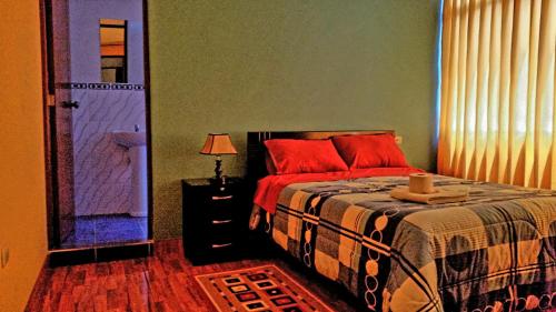 万卡约Hostal Los Pinos的一间卧室配有一张带红色枕头的床和一扇门