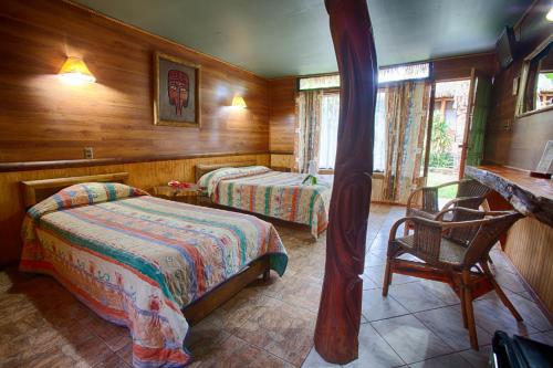 安加罗阿玛妮威酒店的一间卧室配有两张床、一张桌子和一把椅子
