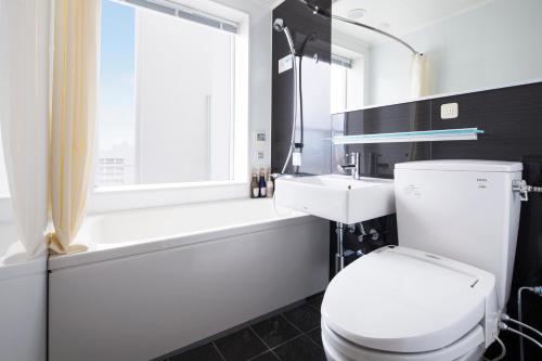 大分MYSTAYS 大分酒店的浴室配有卫生间、浴缸和水槽。