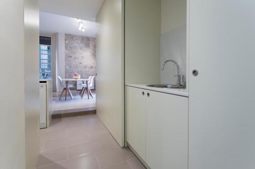 赫罗纳Bravissimo Cort Reial-1B的厨房配有白色橱柜、水槽和桌子