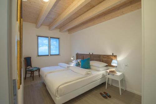 德利纳La Gazza Ladra Apartments - Garda Chill Out的卧室配有一张白色大床和一把椅子