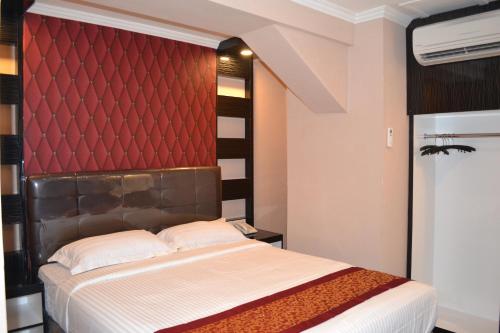 邦加槟港Puncak Budget Hotel的一间卧室配有一张红色床头板的床