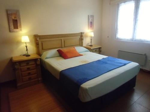 阿霍Apartamento Ajo的一间卧室配有一张大床、两张桌子和两盏灯。