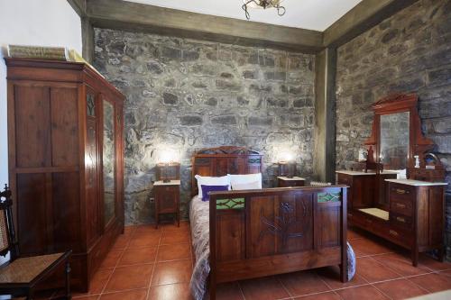 卡佩拉什Casa do Vale do Sossego的一间卧室配有木制家具和石墙