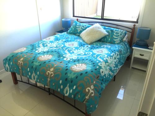 蚬壳港蚬壳港慵懒时光别墅的一张带蓝色棉被和枕头的床