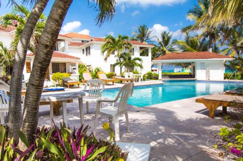 圣佩德罗Tradewinds Paradise Villas的游泳池旁带桌椅的天井