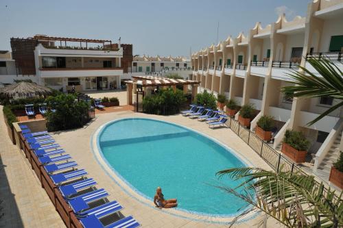 托雷瓦多Cala Saracena Resort的享有酒店游泳池的景色,设有躺椅