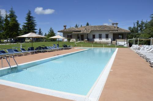 乌尔比诺Agriturismo Cà Mignone的一个带椅子的游泳池以及一座房子
