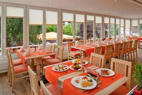 菲施帕克酒店的餐厅设有红色的桌椅和窗户。