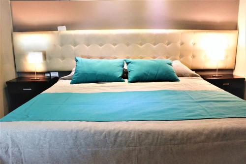 门多萨Kitek Hotel Boutique的一间卧室配有一张带蓝色枕头的大床