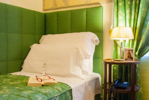 锡拉库扎多莫斯马里阿贝尼西尔酒店的一间卧室设有绿色的墙壁和一张带书籍及台灯的床