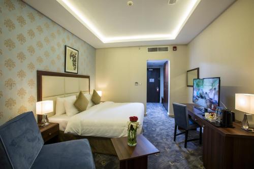 多哈多哈城市酒店的酒店客房配有一张床、一张书桌和一台电视。