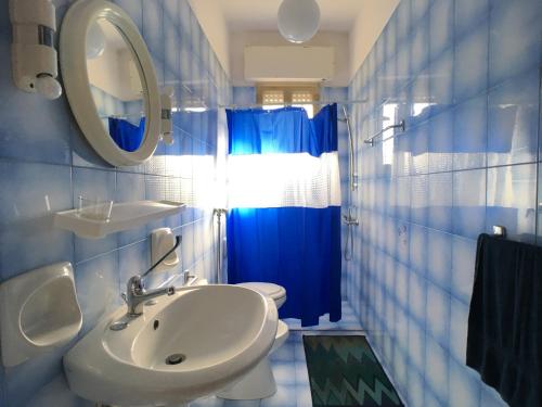 托雷苏达Villetta Gloria的浴室设有水槽和蓝色的浴帘