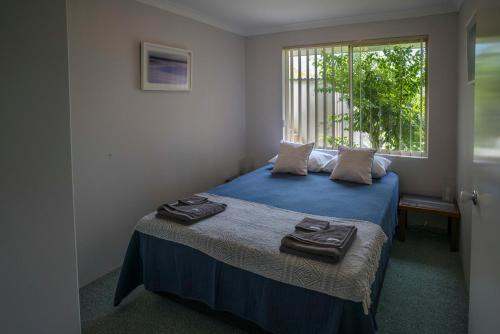 巴瑟尔顿因多由度假屋的一间卧室配有一张带蓝色床单的床和一扇窗户。