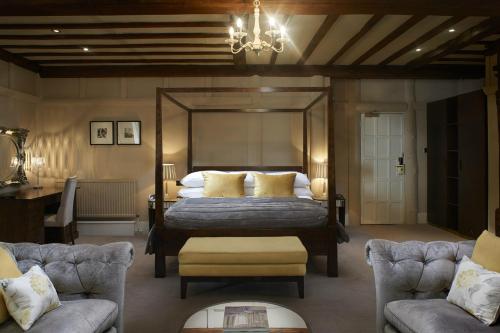 埃尔斯特里The Manor Elstree的一间卧室配有一张床、两把椅子和一个吊灯