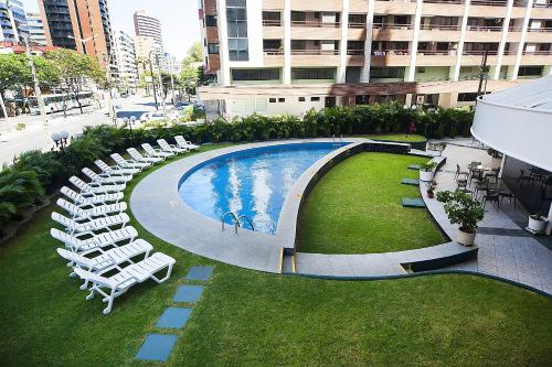 福塔莱萨福塔雷萨舒适酒店的一个带白色椅子和一束桌椅的游泳池