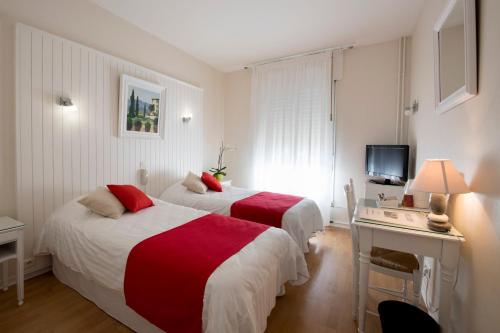 罗德兹比内酒店的配有书桌和电视的酒店客房内的两张床