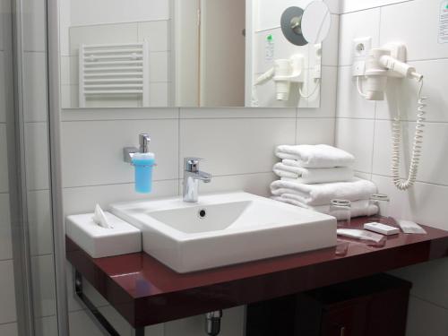 施特拉尔松德库热翰斯德文酒店的浴室配有盥洗盆、镜子和毛巾