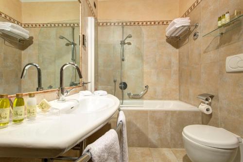 锡耶纳雅典娜酒店的浴室配有盥洗盆、卫生间和浴缸。