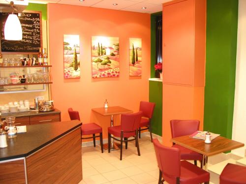 多瑙河畔伊布斯Wohnen beim Bäcker Weinberger的餐厅设有红色的椅子和桌子,墙上挂有绘画作品