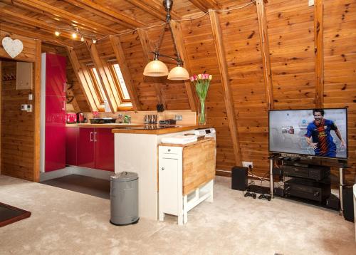 Grafham格拉弗姆水上山林小屋的一间带木墙的厨房和客房内的电视