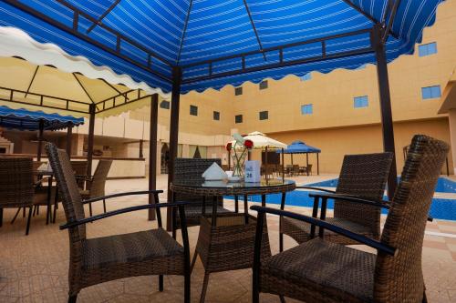 阿尔阿尔Hala Inn Arar Hotel的一个带桌椅的庭院和一个游泳池