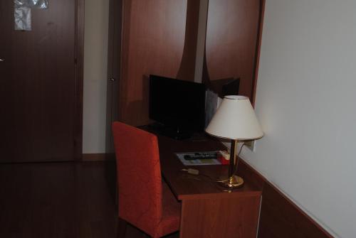 CastelgombertoAlloggio Al Ponte的客房设有带台灯的书桌和电视。