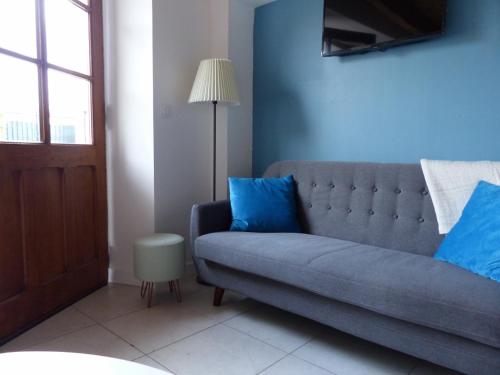 圣若里奥Maison de charme " Les Cyclamens"的客厅里设有蓝色的沙发,配有灯