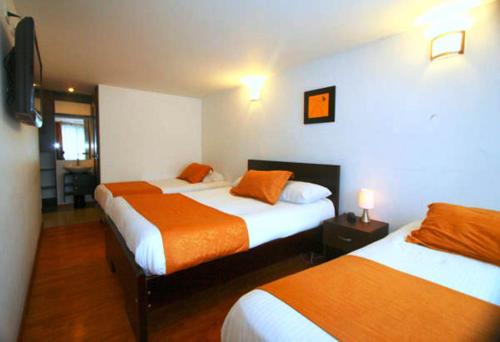 波哥大Hotel Expo Inn Embajada的酒店客房带两张带橙色床单的床