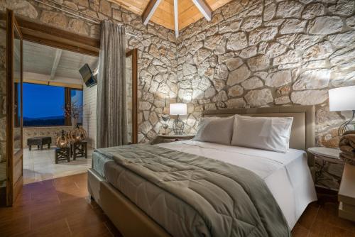 沃丽曼村Tramonto Villa的一间卧室设有一张大床和石墙