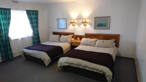 兰伯特湾Lamberts Bay Hotel的酒店客房设有两张床和窗户。