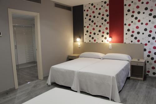 Torrente de CincaHotel Siskets的卧室配有白色的床和带波卡点的墙壁。