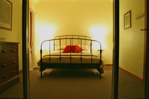 卡斯尔梅恩巴特沃思度假屋的一间卧室配有一张带红色枕头和镜子的床