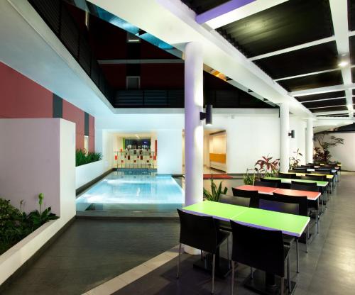 万隆万隆阿马瑞斯酒店的大楼内一个带桌椅的游泳池