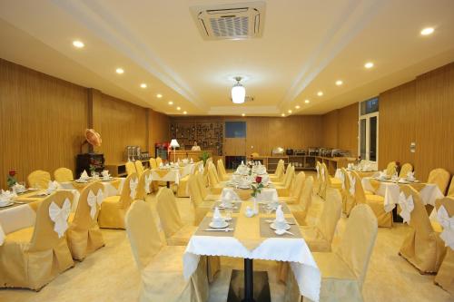 岘港红宫酒店的宴会厅配有白色的桌子和黄色的椅子