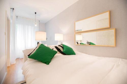 萨格勒布Hella Apartment的卧室内的一张带绿色枕头的白色床