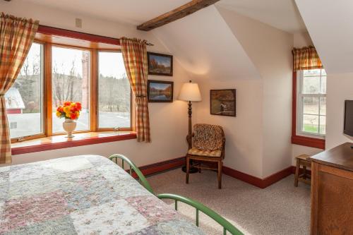 费尔法克斯Inn at Buck Hollow Farm的一间卧室配有一张床、一把椅子和窗户。
