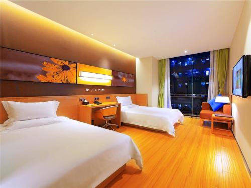 XinzhengzhanIU酒店·郑州新郑西亚斯学院店的酒店客房配有两张床和一张书桌
