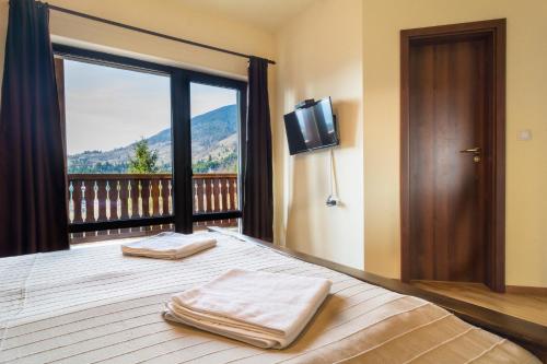 科利比塔Pensiunea Lac Colibita的一间卧室设有一张床,阳台配有电视