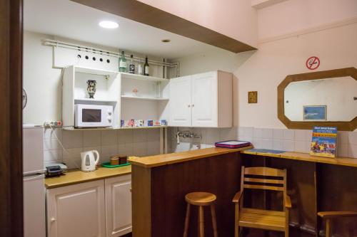 雅典坦普酒店的厨房配有白色橱柜和带凳子的台面