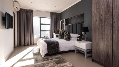约翰内斯堡Odyssey Luxury Apartments - Back Up Generator的一间卧室设有一张大床和一个大窗户