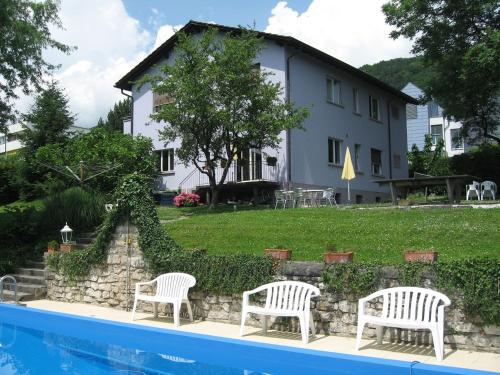拉诺伊韦维尔加尔尼卡门别墅酒店的游泳池旁带两把白色椅子的房子