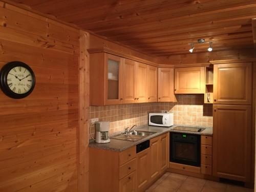 西克斯特瀑布小屋的厨房配有木制橱柜和墙上的时钟
